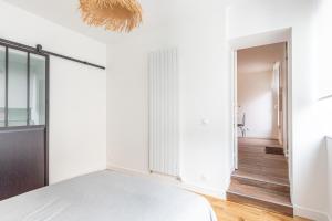 a bedroom with white walls and a bed and a hallway at Suite in Suresnes