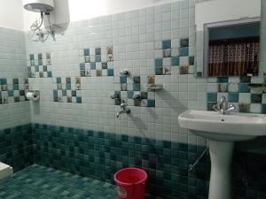a green tiled bathroom with a sink and a mirror at Mandavya homestay in Pelling