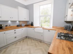 una cucina con armadietti bianchi e pavimenti in legno di Flat 2 Tyn Y Caeau a Menai Bridge