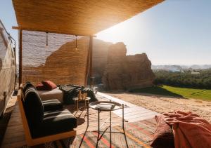 アル・ウラーにあるCaravan by Habitas AlUlaのソファ付きの山の景色を望む客室です。