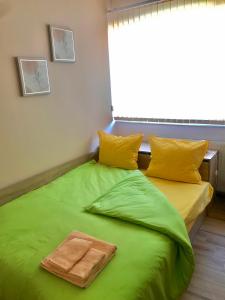 uma cama verde com duas almofadas e uma toalha em Comfort Luxury Apartments em Vratsa