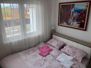a small bedroom with a bed with pink sheets and pillows at Tri palme in Banja Koviljača