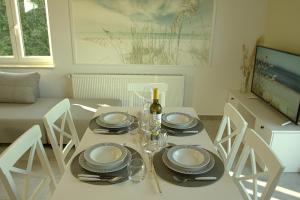 a white table with plates and glasses and a bottle of wine at Harbor apartments 2 in Opatija