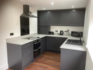 a kitchen with black cabinets and white counter tops at Fully Accessible - Disability Adapted Holiday Cottage - Skegness in Ingoldmells