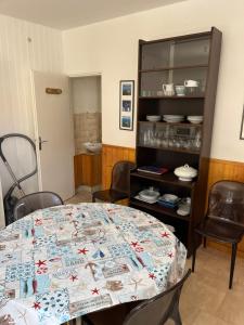 a dining room with a table and a shelf with dishes at Petite maison au coeur du village in Mesquer