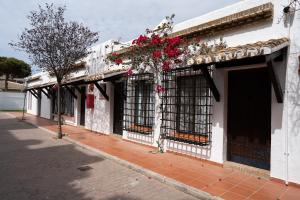 un edificio blanco con ventanas y flores. en Hotel El Cortijo Matalascañas, en Matalascañas