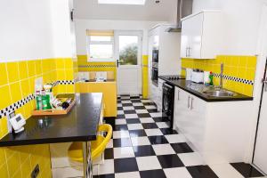 a yellow and white kitchen with a checkered floor at Alexander Apartments Northumberland in Blythe