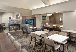 Sonesta ES Suites Raleigh Durham Airport Morrisville في موريسفيل: مطعم بطاولات وكراسي ومدفأة