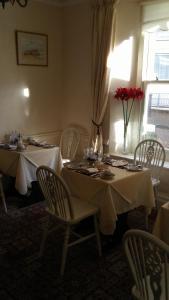 a dining room with two tables and chairs and a window at MYRTLE HOUSE HOTEL TENBY in Tenby