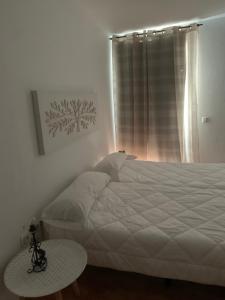 Un dormitorio con una gran cama blanca y una mesa en Apartahotel Playa Conil en Conil de la Frontera