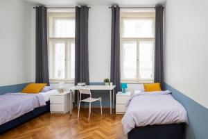 a bedroom with two beds and a desk and two windows at Letná Apartments in Prague