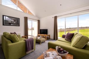 a living room with two green couches and a tv at Elderburn Lodges in St. Andrews