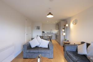 a living room with two couches and a kitchen at Southbank Leeds Apartment. New! With Free Parking in Leeds