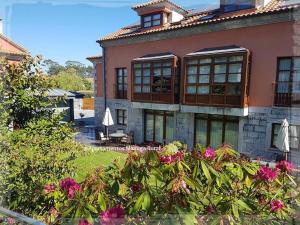 a large pink building with windows and flowers at Apartamentos Mazuga Rural in Po