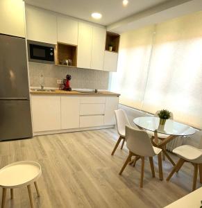 cocina con mesa de cristal y armarios blancos en Apartamentos Aranda - VUT- La Cepa I - II, en Aranda de Duero