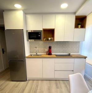 cocina con armarios blancos y nevera de acero inoxidable en Apartamentos Aranda - VUT- La Cepa I - II, en Aranda de Duero