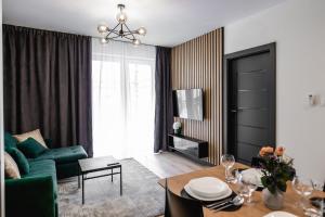 MKM Apartments Lublin في لوبلين: غرفة معيشة مع أريكة خضراء وطاولة