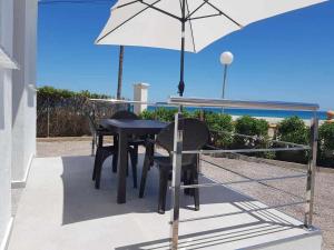 a table and chairs with an umbrella on a patio at Apartamentos Cap y Corp in Alcossebre