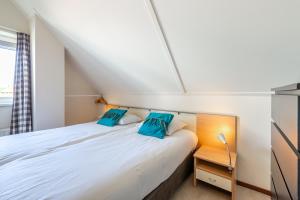 a small bedroom with a bed with blue pillows at Antibes 240 - Kustpark Village Scaldia in Hoofdplaat