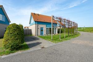 una casa azul con una valla al lado de una carretera en Antibes 240 - Kustpark Village Scaldia, en Hoofdplaat