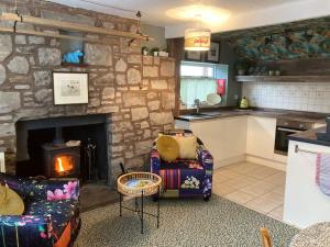 a kitchen and a living room with a stone fireplace at The Wee Cottage in Drumnadrochit