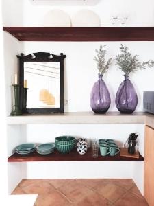 three purple vases sitting on a shelf with dishes at Lobeira - Centenary country house and gardens in Beja