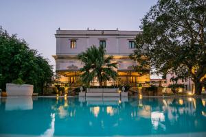 un edificio con piscina di fronte ad esso di Hotel Parco delle Fontane a Siracusa