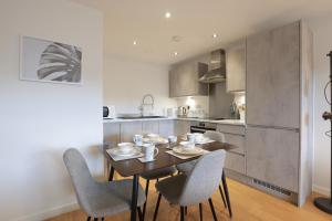 une salle à manger avec une table et des chaises dans une cuisine dans l'établissement Southbank Leeds Apartment. New! With Free Parking, à Leeds