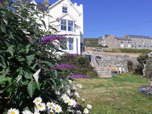 a white house with flowers in the yard at Talarfor Barmouth in Barmouth