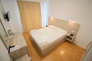 a small bedroom with a white bed and wooden floors at Sun N Blue Hotel in Sarandë