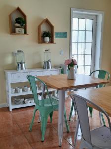 cocina con mesa de madera y sillas verdes en Smiling Places - Guest House in Labruge en Labruge