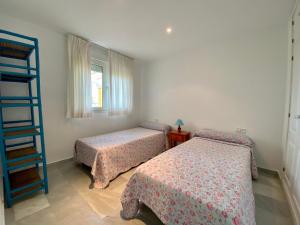 a bedroom with two beds and a ladder and a window at Entre hoyos y la playa Grupo AC Gestion in Novo Sancti Petri
