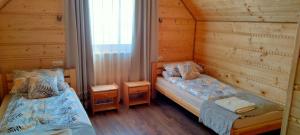 two twin beds in a room with wooden walls at Gospodarstwo Agroturystyczne Bieszczadzki Bliźniak in Baligród
