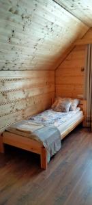 a bed in a room with a wooden wall at Gospodarstwo Agroturystyczne Bieszczadzki Bliźniak in Baligród