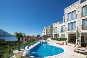 a swimming pool with a palm tree next to a building at Family Lux Apartments - Lemon Garden and Pool in Becici
