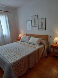 a bedroom with a bed and two lamps and a window at Can Che in Cala Galdana