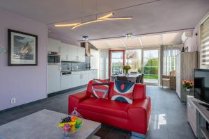 ein Wohnzimmer mit einem roten Stuhl und eine Küche in der Unterkunft Antibes 198 - Kustpark Village Scaldia in Hoofdplaat