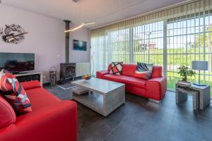 ein Wohnzimmer mit roten Sofas und einem TV in der Unterkunft Antibes 198 - Kustpark Village Scaldia in Hoofdplaat