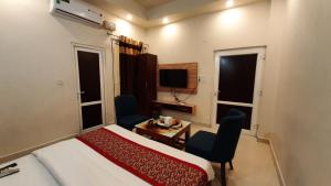 a bedroom with a bed and two chairs and a tv at Hotel Ventures Inn in Amritsar