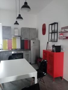 une cuisine avec une table blanche et une armoire rouge dans l'établissement Lo scorcio della Neapolis Accogliente appartamento pressi parco Neapolis, à Syracuse