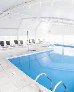 a large swimming pool with chairs in a building at Green Sea Apart Hotel in Pinamar