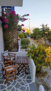 a patio with two benches and a table and flowers at Aegean Star Hotel in Karavostasi