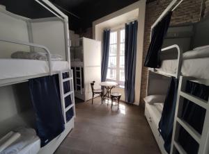 pokój z dwoma łóżkami piętrowymi i stołem w obiekcie Black Swan Hostel Sevilla w Sewilli