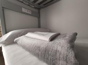 białe łóżko z poduszką na górze w obiekcie Black Swan Hostel Sevilla w Sewilli +34 zdjęcia