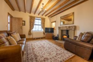 a living room with leather furniture and a fireplace at Threp'nybit Cottage in Carlton