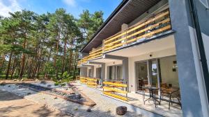 a house with a balcony with a table and chairs at Apartamenty Leśna Plaża in Brenno