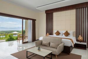 a bedroom with a bed and a couch and a balcony at Semabu Hills Hotel Nusa Penida in Nusa Penida