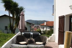 een patio met een tafel, een parasol, stoelen, een tafel en een stoeltje bij Appartement au calme à Hendaye in Hendaye