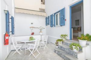 eine Terrasse mit Tisch und Stühlen und blauen Fensterläden in der Unterkunft Argiro in Tinos