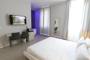Schlafzimmer mit einem Bett, einem Schreibtisch und einem TV in der Unterkunft Cadorna Luxury Hotel in Mailand